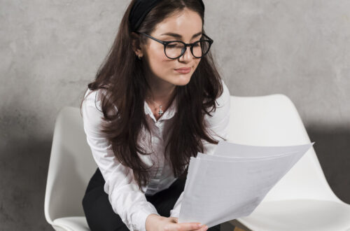 mulher sentada pensativa enquanto le um laudo