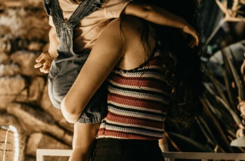 Mulher segura sua filha ambas de costas