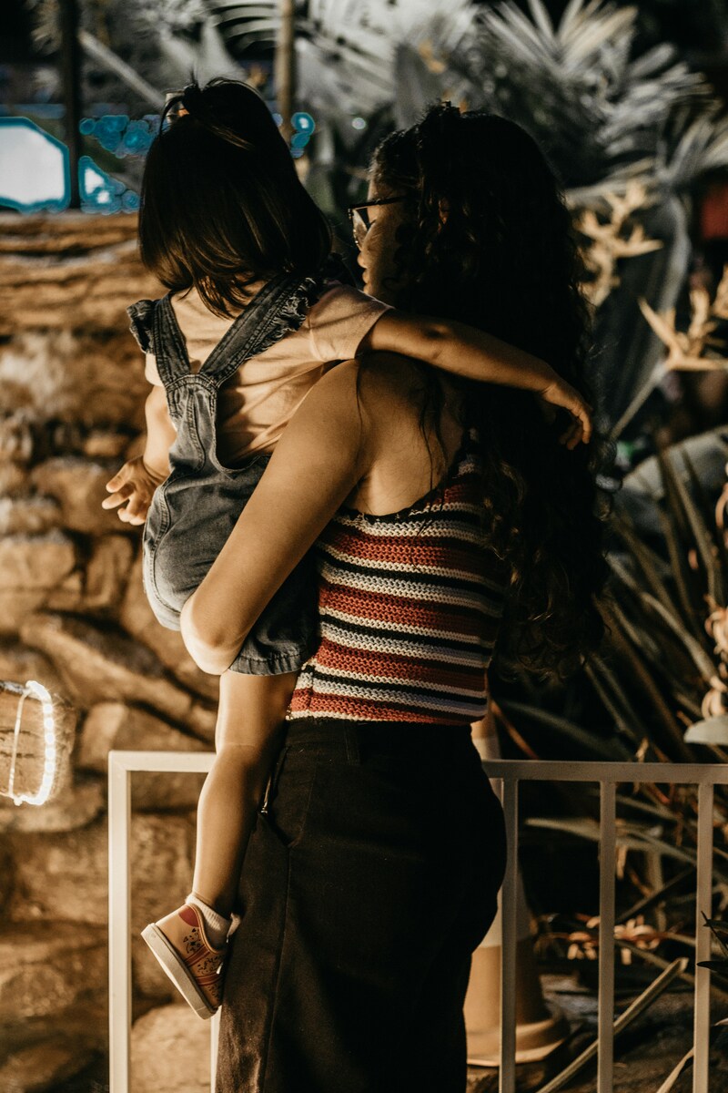 Mulher segura sua filha ambas de costas